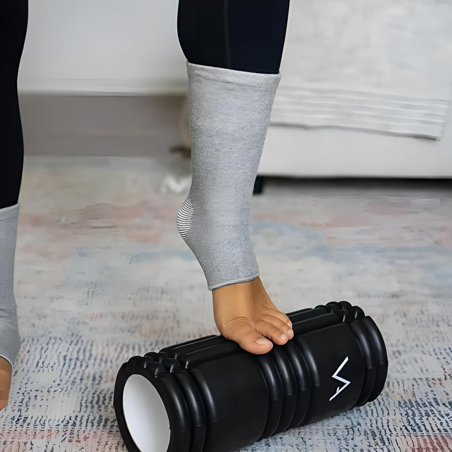 Foot massaging on black foam roller, person in grey compression socks, IndianChic wellness product