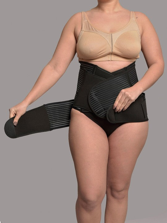 Woman wearing 3-in-1 postnatal shapewear belt in black, adjusting waist strap
